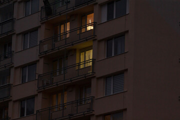 At night, a tall building adorned with numerous windows and balconies is beautifully illuminated, creating a vibrant atmosphere