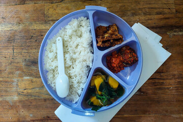 Rice side dishes in a blue Tupperware lunch box on the table
