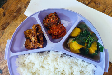 Rice side dishes in a blue Tupperware lunch box on the table