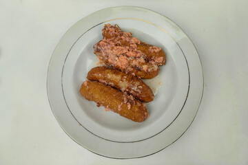 Banana cake is served on a white plate on a white table