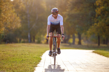 Cyclist riding along a path in a park during a sunny autumn day