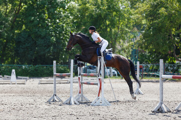 Female equestrian rider jumps over obstacles during a show jumping event