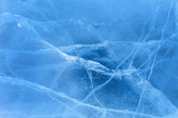 Beautiful winter natural ice texture of frozen Baikal Lake in cold day. Blue ice surface with pattern of white cracks. Natural icy seasonal background. Mock up, copy space, flat lay, blank, top view