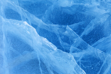 Beautiful crystalline ice texture. Cold background of blue ice with cracks and lines of icy surface of frozen Baikal Lake on winter. Unique ice pattern. Top view, flat lay, mockup, copy space,