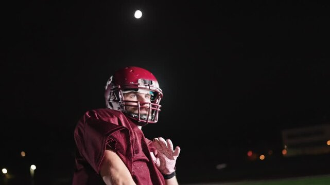 An American football player practicing throwing and catching the ball on a field