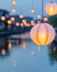 Fototapeta premium Festive luminous lanterns drift serenely above a calm waterway as twilight descends, casting enchanting reflections on the surface.