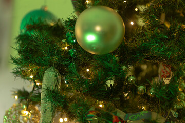 A detailed closeup view of a beautifully decorated Christmas tree adorned with shiny green ornaments that catch the light