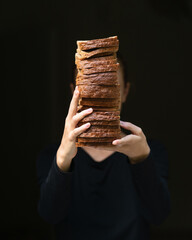 Wheat rye toast, Dark Bread Slices in hands. Stack of Sliced Homemade bread bricks. Breakfast,...
