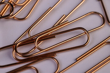 large-sized copper paper clips lie on white blank paper