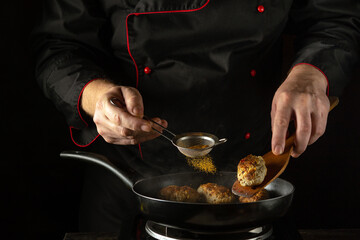 A chef expertly seasons meatballs with paprika in a dark kitchen, focusing on perfecting the flavour. European cuisine