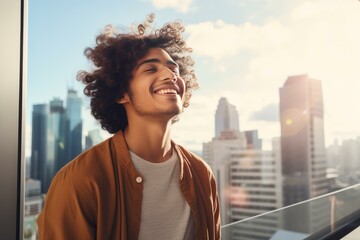 Fototapeta premium Carefree man breathing fresh air and smiling on a balcony with a cityscape in the background
