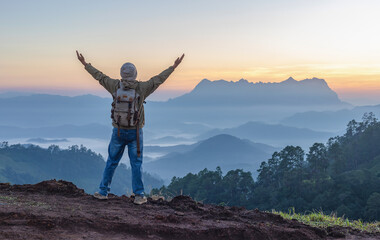 Winner Male hiker with backpack standing hands raised on mountain landscape and beautiful view sunset background.Hiker men's hiking living healthy active lifestyle.