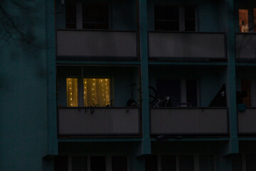 At night, the balconies of a tall building are beautifully illuminated, creating a stunning visual effect against the dark sky