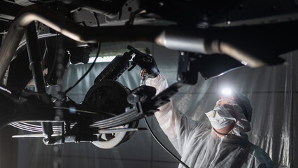 The master sprays an anti-corrosion compound on the bottom of the car. 