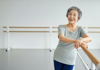 Happy senior woman enjoying her active retirement, leaning on a barre in a dance studio, embodying a healthy and fulfilling lifestyle