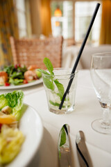 Erfrischendes Getränk mit Minze neben einem sommerlichen Salat