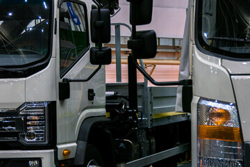 Two medium-duty white trucks. The vehicles are photographed in close-up, allowing for a detailed...
