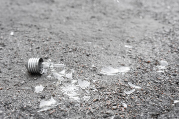 Broken light bulb and it's glass fragments lying on ground, Shattered incandescent lamp with broken...