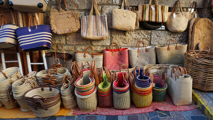 Display of colorful handmade straw woven bags and baskets for sale at the market in Le Lavandou, Cote d'Azur, France. Natural material, sustainable product.