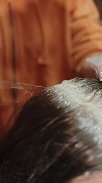Hairdresser applying dye to an elderly woman's hair, effectively covering gray roots for a fresh and vibrant look