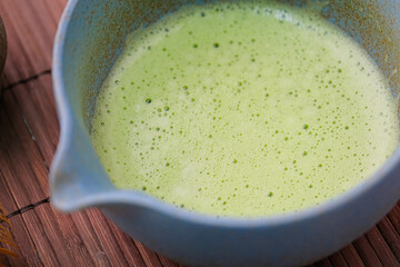 closeup of green matcha tea whipped in the tea bowl