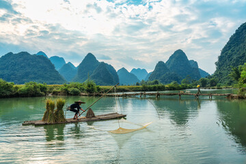 Rural scene of fisherman fishing on wooden raft, surrounded by mountain in sunny day at Phong Nam...