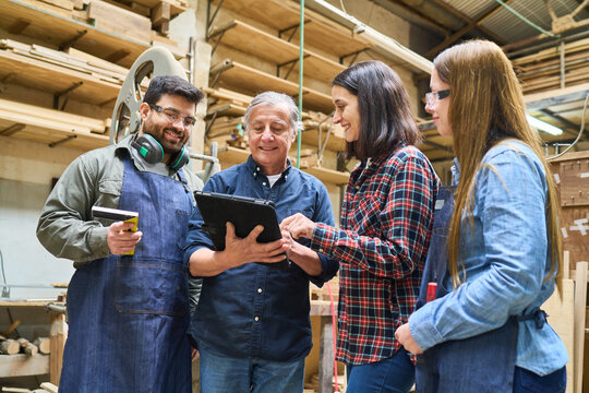 Young workers learning from experienced mentor in lumberyard setting