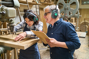 Older and younger workers collaborating in a busy lumberyard workshop