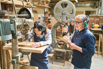Experienced worker training apprentice in carpentry workshop