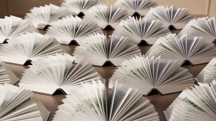 There are open books on a large table, view from above, the books create a geometric pattern