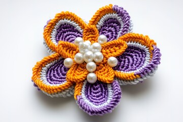Close-up of a vibrant crochet flower brooch with orange and purple yarn and white beads.