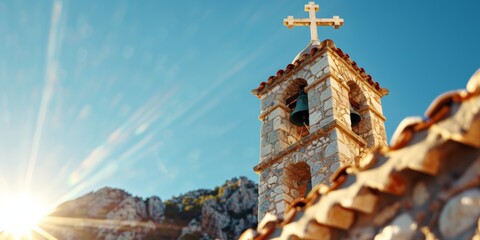 A historic stone bell tower with a cross at the top, set against a bright blue sky, symbolizing faith and heritage.