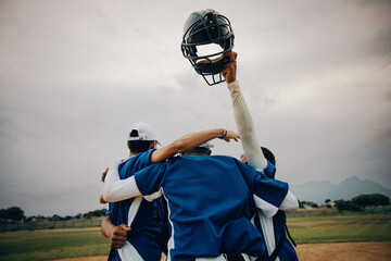 Blue baseball team celebrating victory with players raising helmet in the air on a field