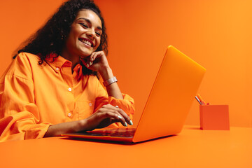 Happy young freelancer jobseeker working online in vibrant monochromatic orange workspace