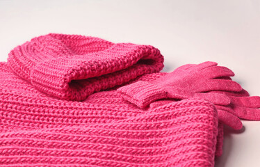 Bright rich pink knitted hat, scarf and gloves. Textured wool. Isolated clothing item on white background. 