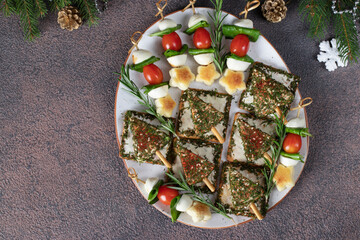 Cheese Christmas trees on crackers and canapes with cherry tomatoes, mozzarella cheese and spinach