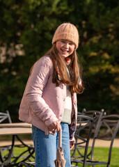 Portrait of joyful, smiling 10-11 years old girl wearing woolen hat. In her hands she holds an umbrella. Outdoor. Happy child.