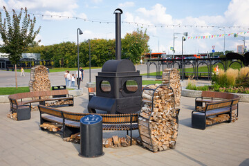 A park with a large fire pit surrounded by benches and a sign. Nizhny Novgorod. Russia