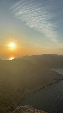 View of white houses on a rocky cliff overlooking the sea at sunset in Folegandros island, Greece