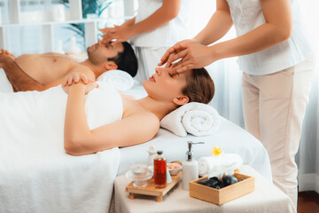 Obraz premium Caucasian couple enjoying relaxing anti-stress head massage and pampering facial beauty skin recreation leisure in dayspa modern light ambient at luxury resort or hotel spa salon. Quiescent