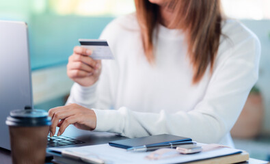 woman holding credit card, and typing on laptop, to shop, and pay via internet, concept of online shopping and services, ordering products at home.