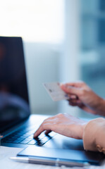 woman holding credit card, and typing on laptop, to shop, and pay via internet, concept of online shopping and services, ordering products at home.