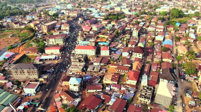 A busy suburb in Freetown, Sierra Leone, showing dense urban buildings, a main road with heavy traffic, and active city life. ty.