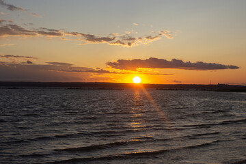 Obraz premium a sunset over a lake with a sunset in the background.