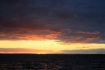 Fototapeta premium a sunset over a lake with a sunset in the background.