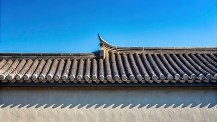 Silhouette of gray house wall with gable Asian style roof against clear blue sky
