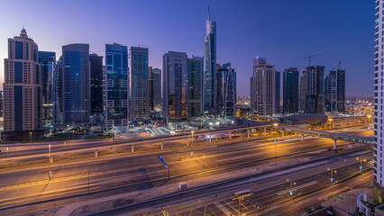 Fototapeta premium Aerial view of Jumeirah lakes towers skyscrapers night to day timelapse with traffic on sheikh zayed road.