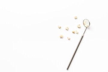 Dental teeth crowns and steel instrument for dental prosthetics, top view. Dentist desk, white background