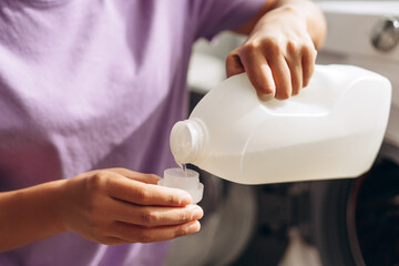 Housekeeper pouring laundry detergent into measuring cup