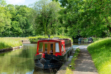 Several canal narrowboats docked along the Llangollen Canal with towpath in Trevor Basin near Pontcysyllte Aqueduct near Trevor, Wrexham, UK